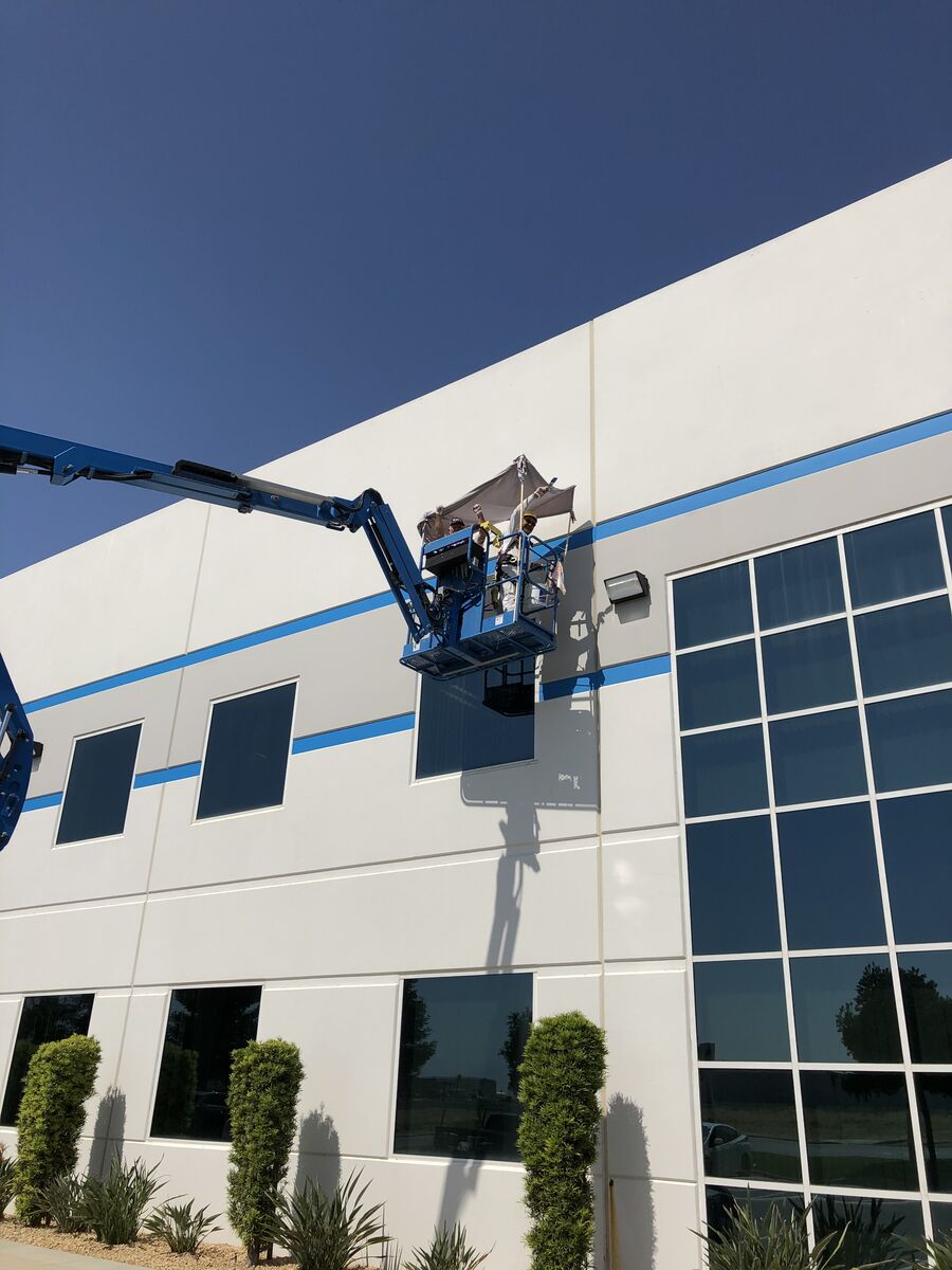 Boom lift at large commercial building during exterior painting